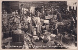 Schwarz-weiße historische Ereigniskarte von der Unwetter-Katastrophe in Berggießhübel am 8. Juli 1927: Arbeiter und Anwohner bei den Aufräumungsarbeiten inmitten von Trümmern und geretteten Haushaltsgegenständen, mit der Seriennummer „22“. Frankiert mit Goethe- und Schiller-Marke, Poststempel Berggießhübel vom 24.9.1927 – ein Zeitdokument des verheerenden Hochwassers in Sachsen.