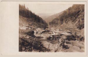 Sepia-Original-Foto-Abzug „Laz. Einrichtung am Kordas-Paß" (Nr. 32) aus dem 1. Weltkrieg: Feldlazarett des k.u.k. Sanitätswesens mit Holzbaracken, gewundenem Bergweg, Soldaten und Pferdetransport in einem steilen, bewaldeten Tal der Julischen Alpen – ein Zeitdokument des Gebirgskriegs an der Isonzo-Front.